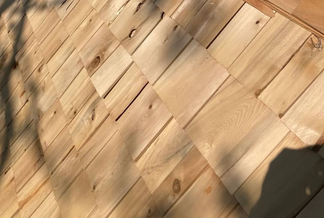 Hand-laid cedar shingle courses in raking afternoon light