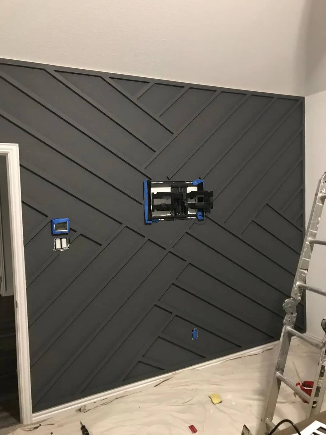 Charcoal chevron batten wall part-finished, with the display mount set and the floor protected