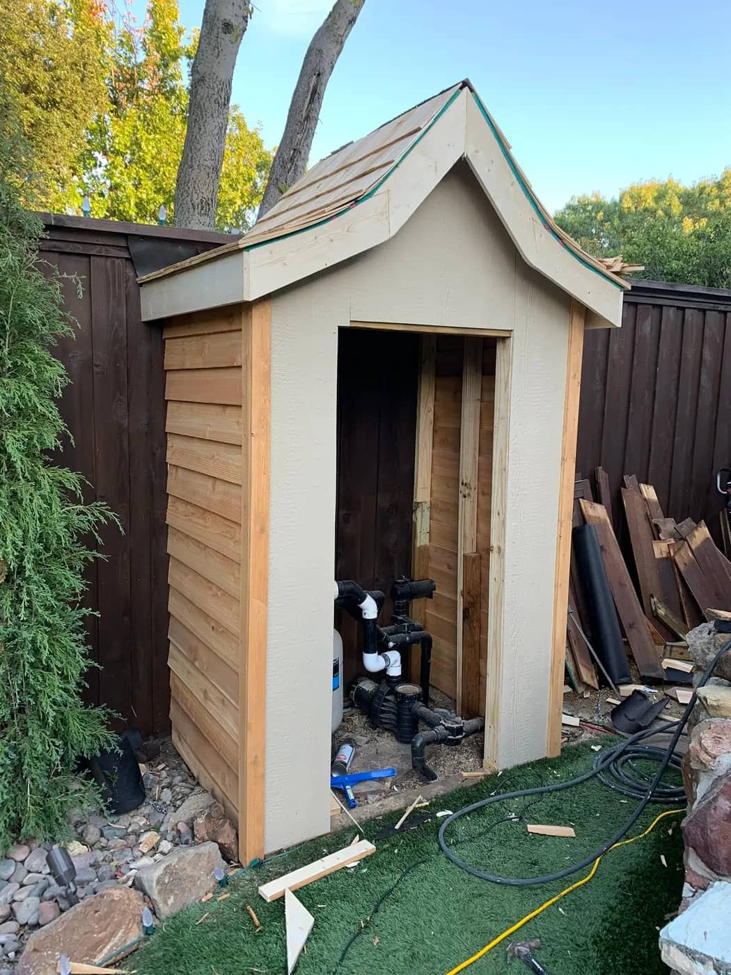 The same garden store part-built, with cedar siding started and the roof framed