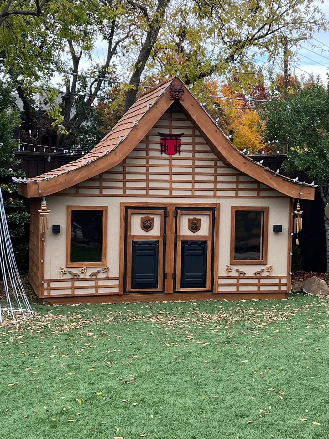 Completed timber-framed garden playhouse with a cedar shingle roof and curved eaves
