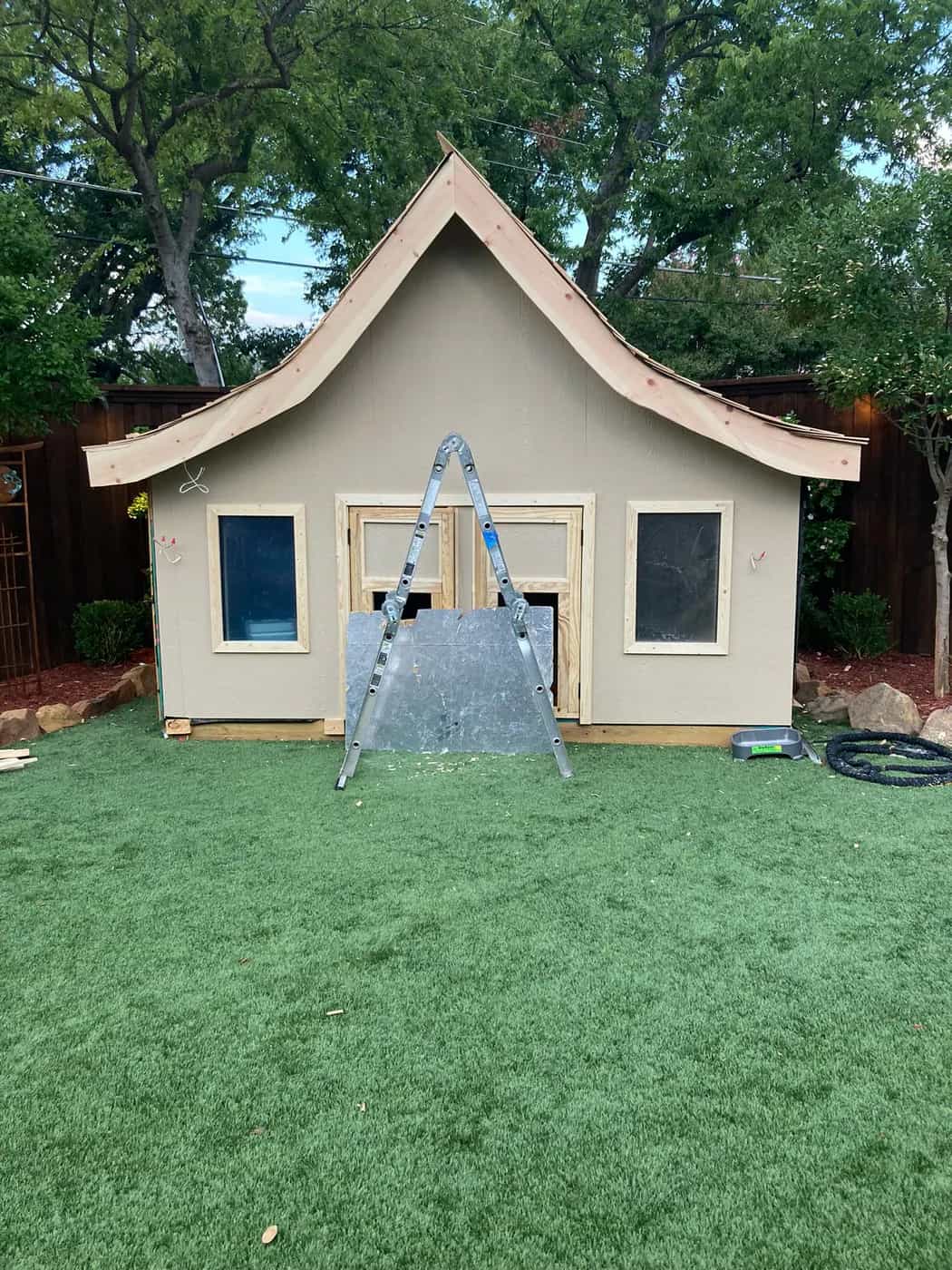 The same garden playhouse mid-build, sheathed and primed with the curved roof framed